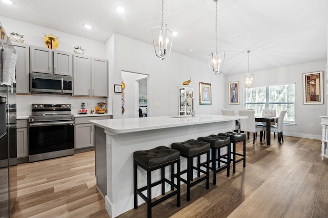 kitchen featuring gray cabinetry, sink, an island with sink, and appliances with stainless steel finishes