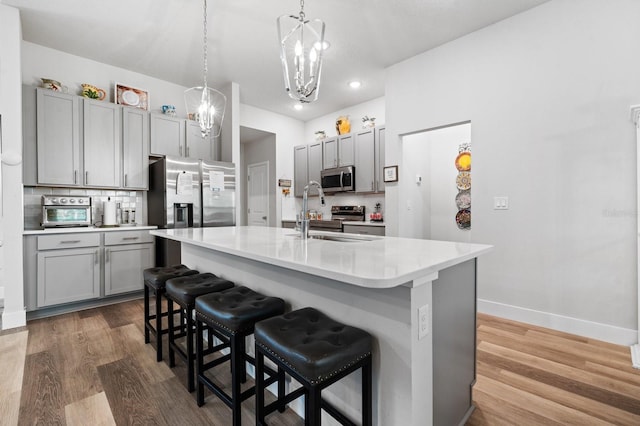 kitchen with backsplash, gray cabinetry, sink, and a kitchen bar
