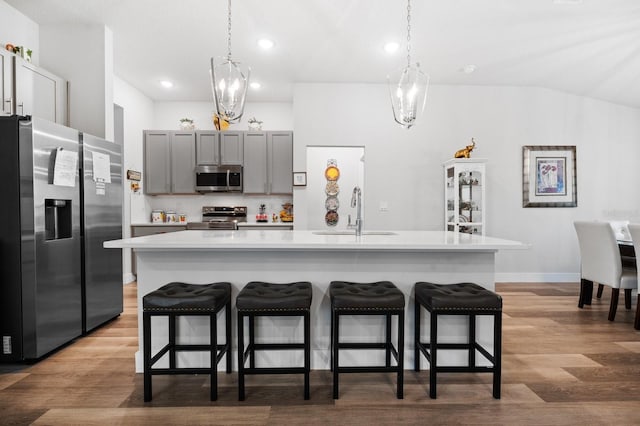 kitchen with sink, gray cabinets, an island with sink, appliances with stainless steel finishes, and decorative light fixtures