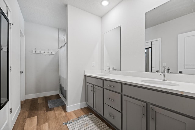 bathroom with hardwood / wood-style flooring, vanity, a shower with curtain, and a textured ceiling