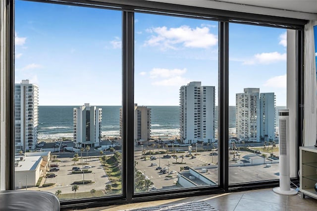 interior space with tile patterned flooring, a water view, and a wall of windows