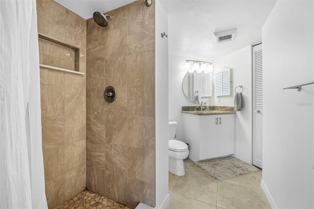 bathroom featuring tile patterned floors, vanity, toilet, and a tile shower