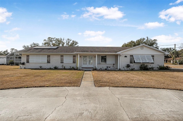 ranch-style house featuring a front yard and solar panels