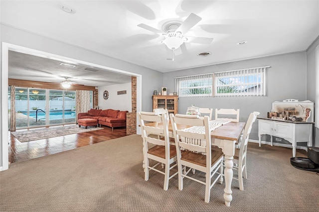 carpeted dining area with ceiling fan