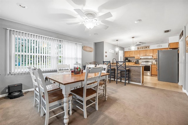 dining area with ceiling fan and light carpet