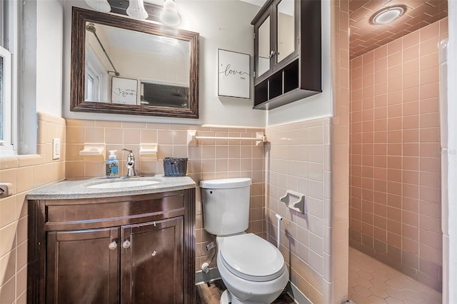 bathroom featuring vanity, toilet, and tile walls