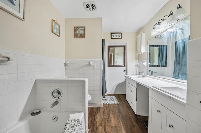 bathroom featuring wood-type flooring, vanity, tile walls, toilet, and a washtub