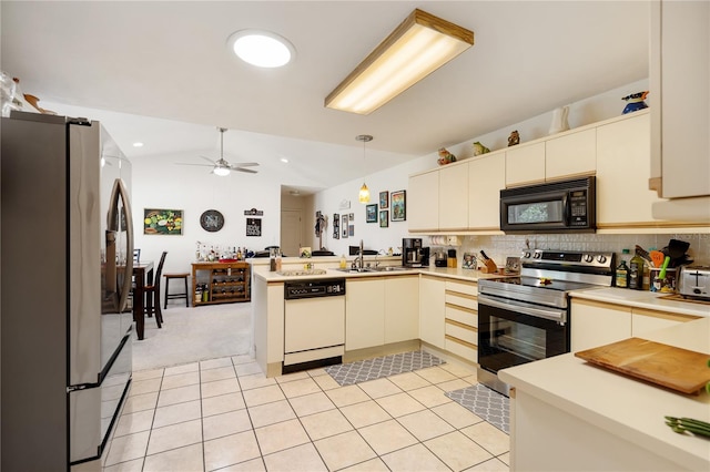 kitchen with kitchen peninsula, appliances with stainless steel finishes, backsplash, ceiling fan, and hanging light fixtures