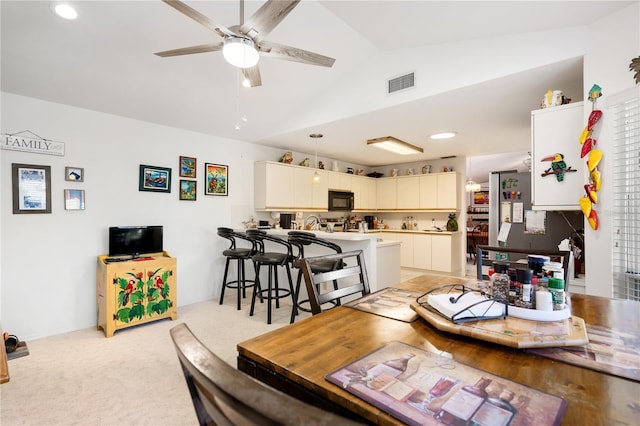 dining space with light carpet, ceiling fan, and lofted ceiling