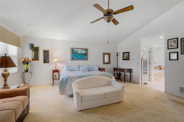 bedroom with ceiling fan, ensuite bathroom, light carpet, and vaulted ceiling