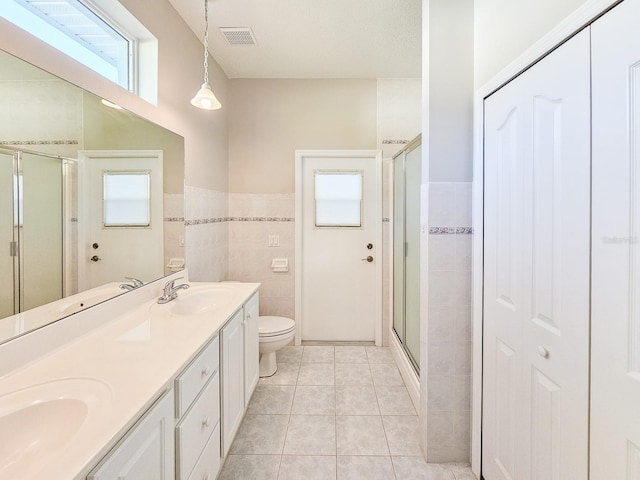 bathroom with toilet, tile patterned flooring, tile walls, an enclosed shower, and vanity