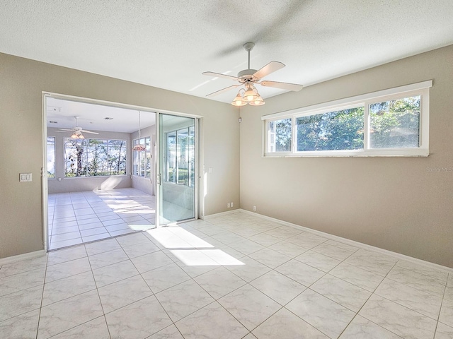 unfurnished room featuring a textured ceiling, ceiling fan, and light tile patterned floors