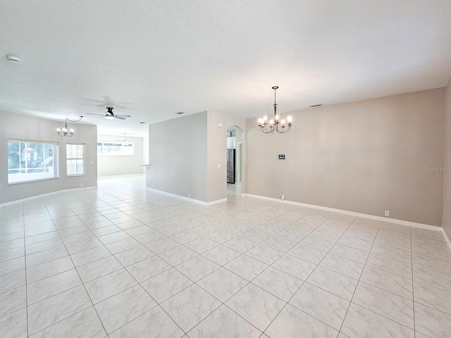 spare room featuring ceiling fan with notable chandelier and a textured ceiling