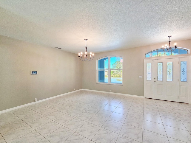 foyer entrance with a textured ceiling and a chandelier