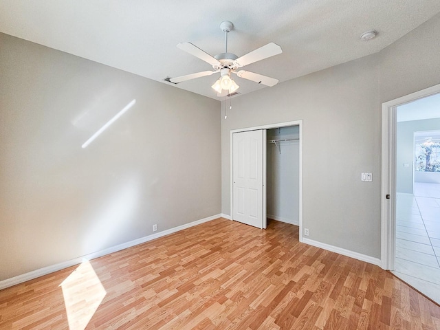 unfurnished bedroom with ceiling fan, light hardwood / wood-style flooring, and a closet