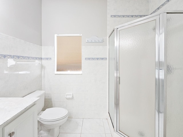 bathroom featuring toilet, a shower with door, vanity, and tile walls