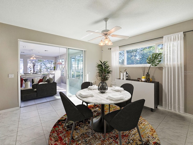 tiled dining area with ceiling fan, a wealth of natural light, and a textured ceiling