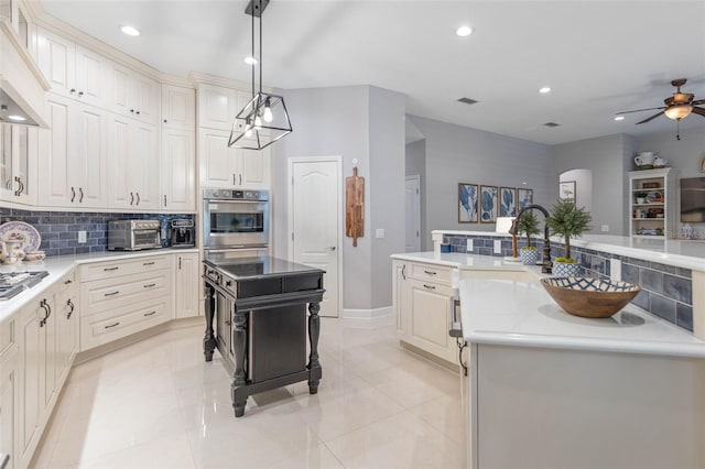 kitchen with backsplash, range hood, a kitchen island, and decorative light fixtures