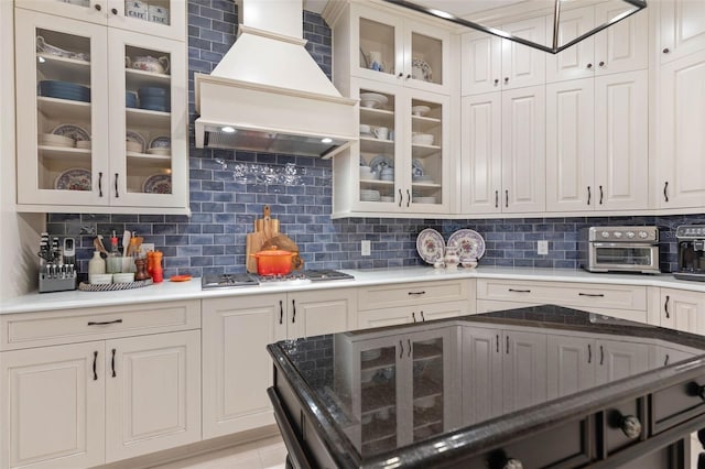 kitchen featuring white cabinetry, stainless steel gas stovetop, decorative backsplash, and custom exhaust hood