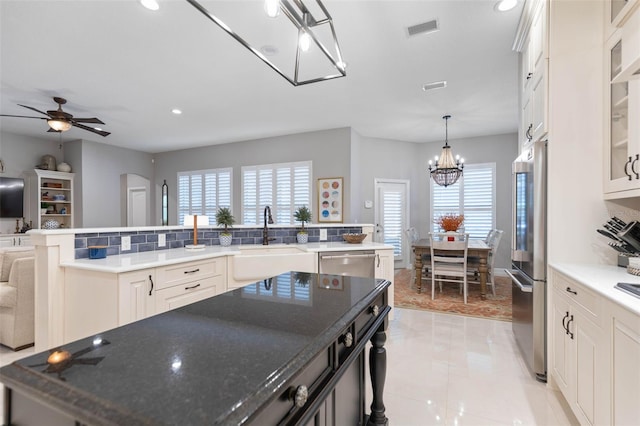 kitchen with sink, stainless steel appliances, backsplash, a large island with sink, and decorative light fixtures