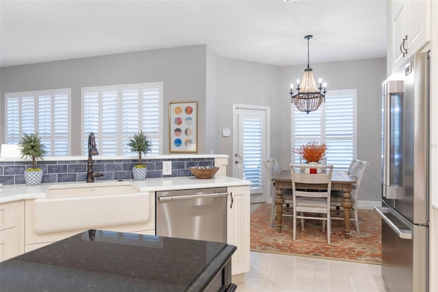 kitchen featuring sink, a chandelier, decorative light fixtures, white cabinets, and appliances with stainless steel finishes