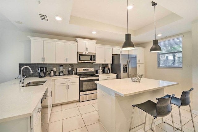 kitchen featuring a tray ceiling, white cabinetry, light tile patterned floors, and stainless steel appliances