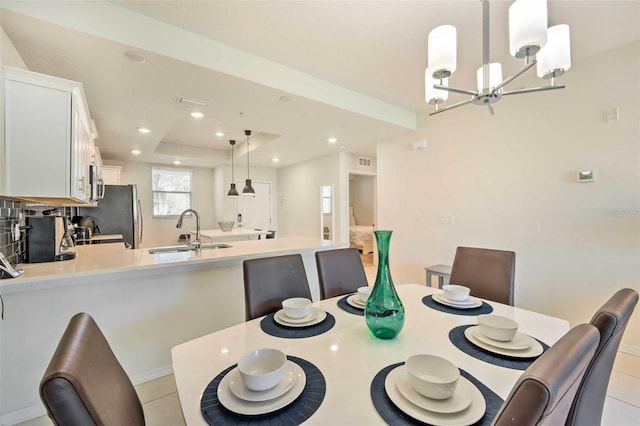 tiled dining area with a chandelier, sink, and a tray ceiling