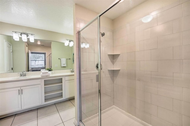 bathroom featuring a textured ceiling, vanity, tile patterned floors, and a shower with door