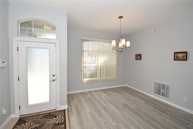 foyer entrance with light hardwood / wood-style floors, an inviting chandelier, and plenty of natural light