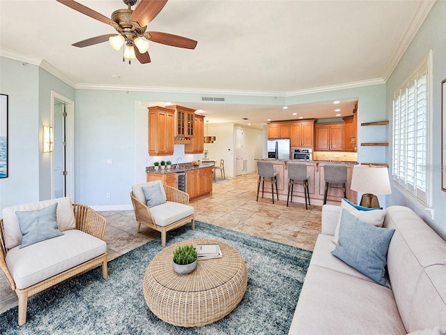 tiled living room with ceiling fan, sink, and crown molding