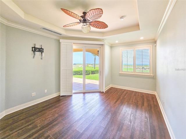 spare room with a tray ceiling, crown molding, ceiling fan, and dark hardwood / wood-style floors