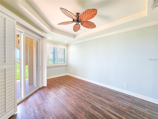 unfurnished room featuring ceiling fan, crown molding, dark wood-type flooring, and a tray ceiling