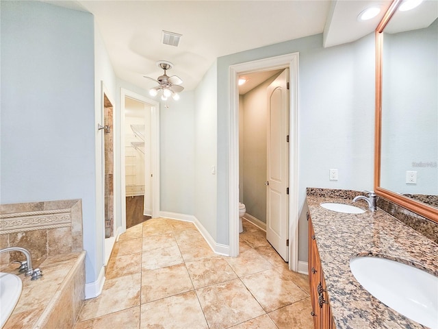 bathroom featuring ceiling fan, tile patterned flooring, tiled bath, toilet, and vanity