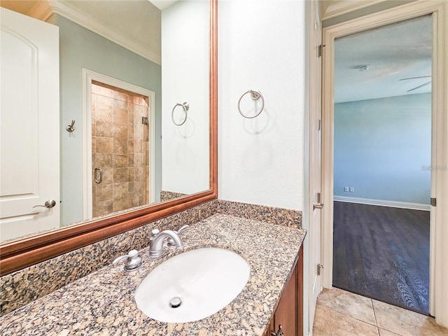 bathroom with tile patterned floors, vanity, a shower with shower door, and crown molding