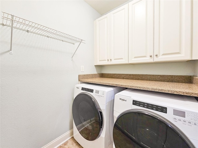 laundry room featuring washer and clothes dryer and cabinets