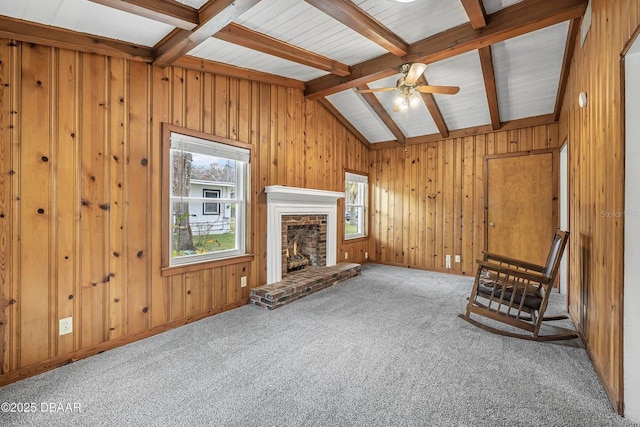 unfurnished room featuring carpet, vaulted ceiling with beams, ceiling fan, and a brick fireplace