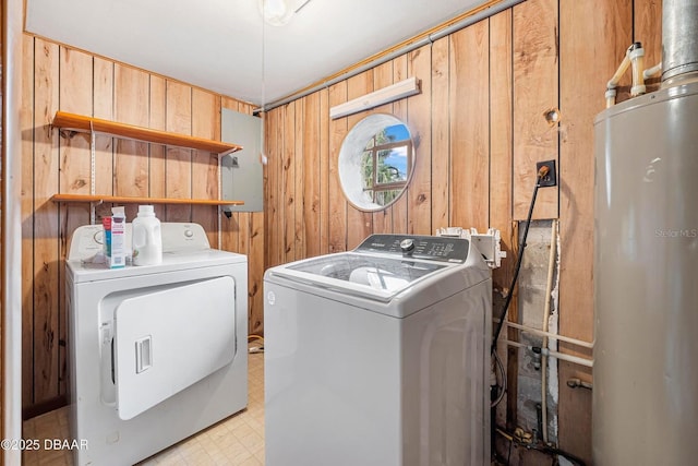 washroom with wood walls, washing machine and dryer, electric panel, and water heater