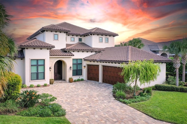 mediterranean / spanish house with a garage and a lawn