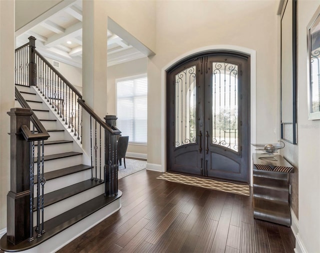 foyer entrance with coffered ceiling, dark hardwood / wood-style floors, beam ceiling, and french doors