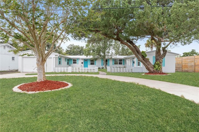 ranch-style home featuring a front lawn, covered porch, and a garage