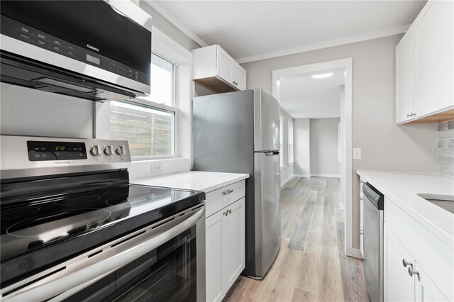 kitchen featuring stainless steel appliances, light hardwood / wood-style flooring, crown molding, decorative backsplash, and white cabinets