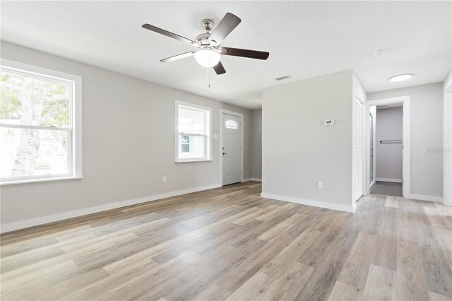 empty room with ceiling fan, a textured ceiling, and light wood-type flooring