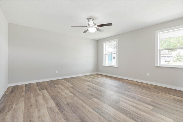 unfurnished room featuring a wealth of natural light, ceiling fan, and light wood-type flooring