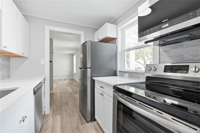 kitchen featuring stainless steel appliances, crown molding, decorative backsplash, white cabinets, and light wood-type flooring