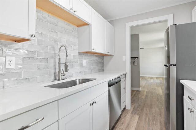 kitchen featuring white cabinets, sink, light hardwood / wood-style flooring, decorative backsplash, and appliances with stainless steel finishes