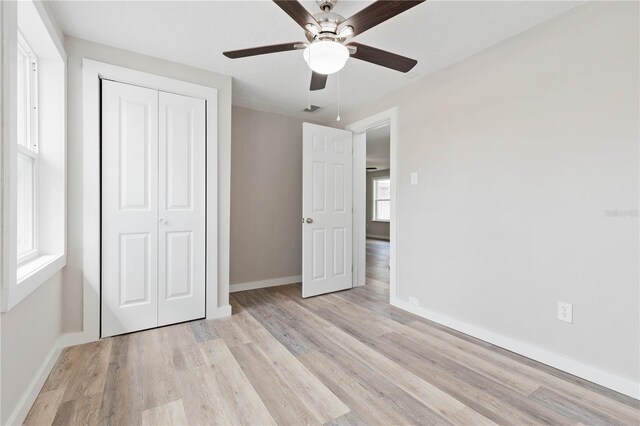 unfurnished bedroom featuring ceiling fan, a closet, and light hardwood / wood-style flooring