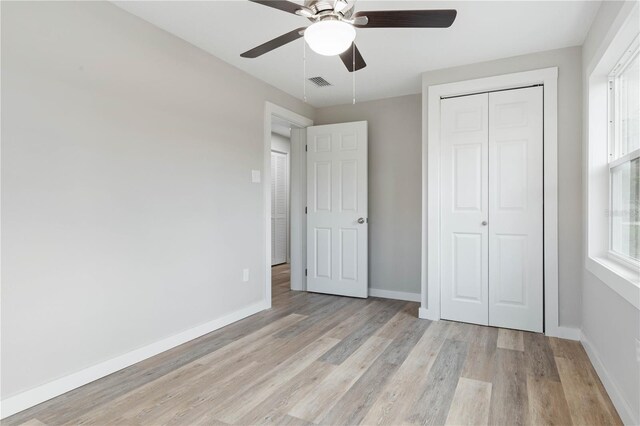 unfurnished bedroom with ceiling fan, a closet, and light wood-type flooring