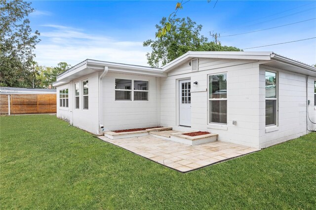 back of property with a patio area and a lawn