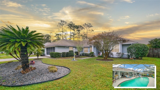 back house at dusk with a fenced in pool, glass enclosure, and a yard