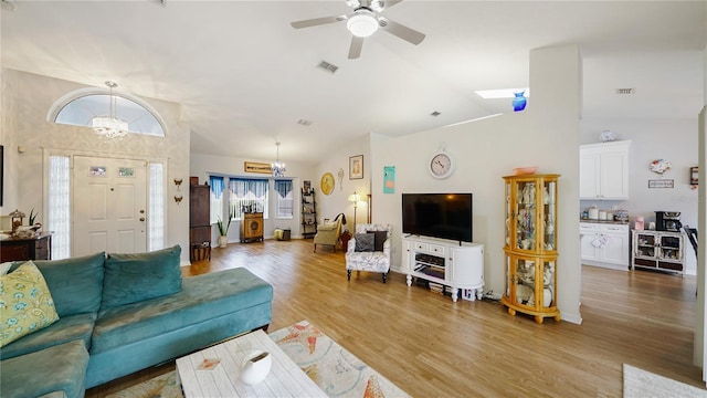 living room featuring hardwood / wood-style flooring, ceiling fan with notable chandelier, and lofted ceiling